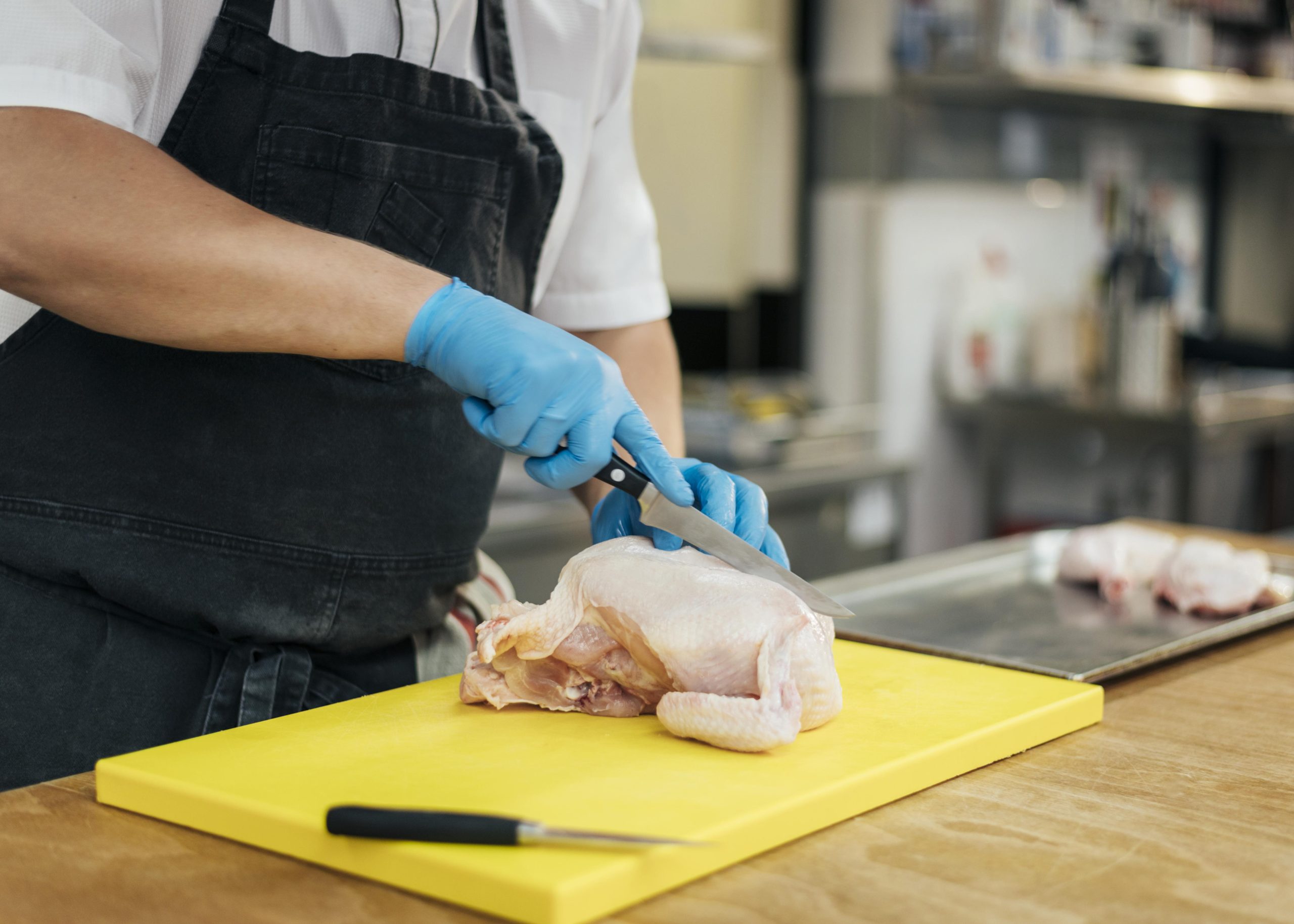 side-view-chef-with-apron-gloves-cutting-chicken distributor ayam potong